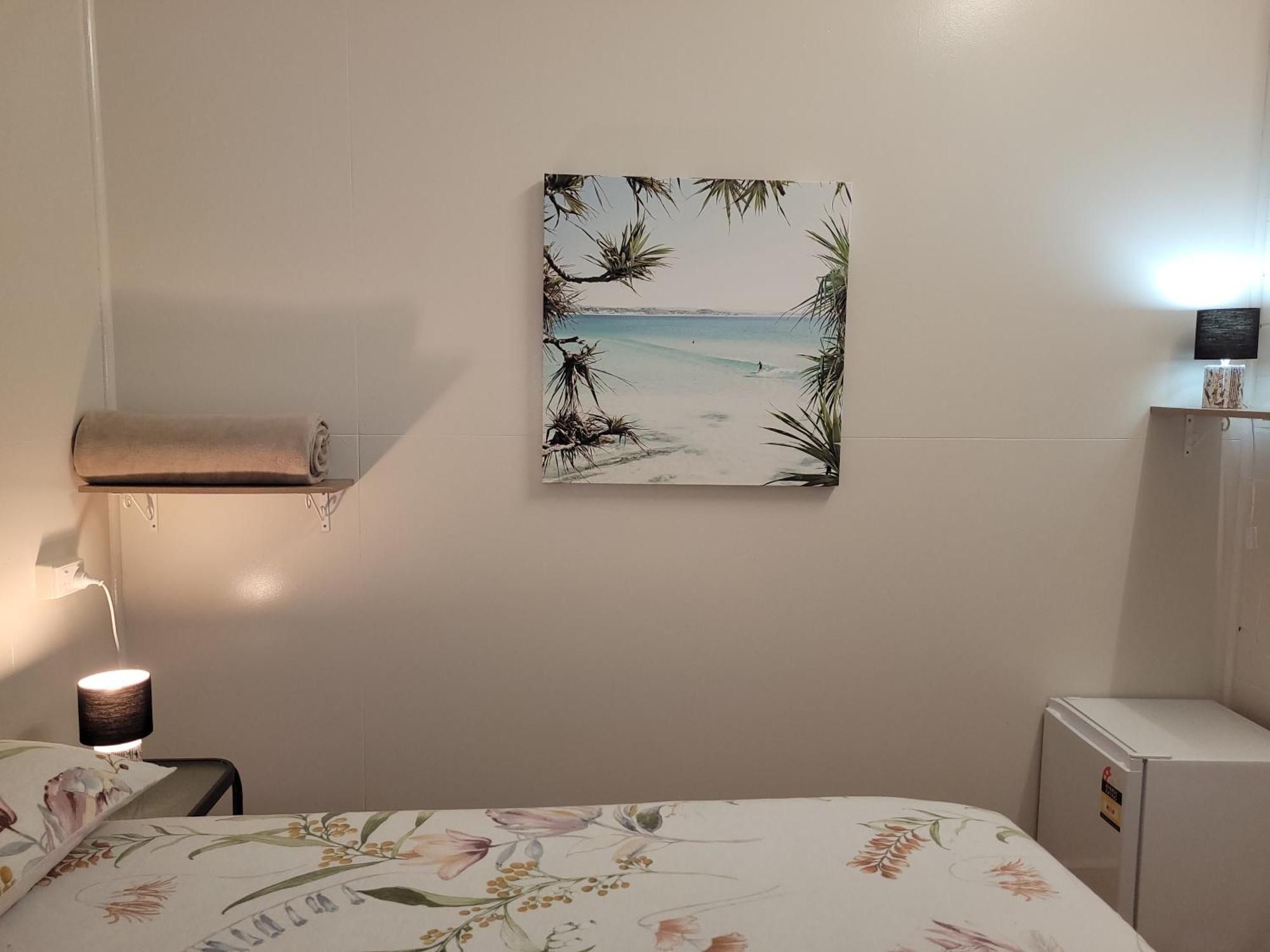 Travellers Paradise Cairns Ngoại thất bức ảnh A photograph of a bedroom with a bed, a nightstand, a lamp, a painting, and a television